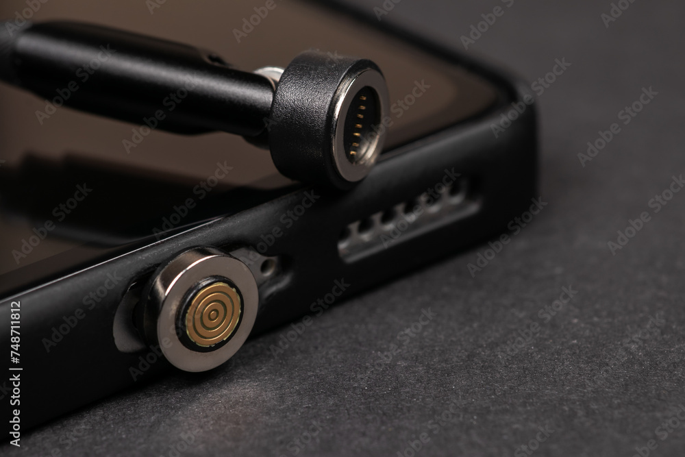 Magnetic charger wire for phone on dark background Magnetic charger wire for phone on dark background