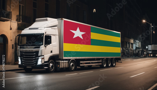 A truck with the national flag of Togo depicted carries goods to another country along the highway. Concept of export-import,transportation, national delivery of goods.