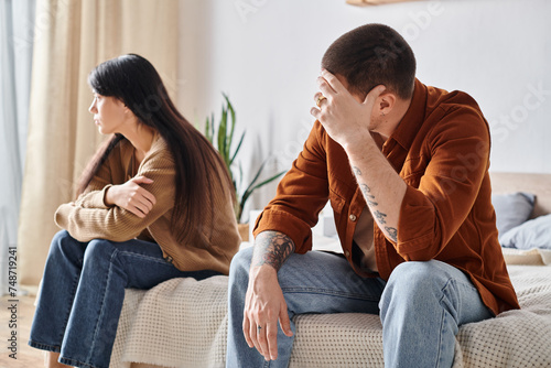 Foto upset young interracial couple sitting in bedroom at home, relationship difficul