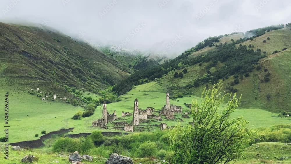 View of the medieval Targim tower complex in the Caucasus mountains surrounded by greenery. The Caucasus Mountains on a cloudy day in Ingushetia. Russia, 4K. View of the medieval Targim tower complex in the Caucasus mountains surrounded by greenery. The Caucasus Mountains on a cloudy day in Ingushetia. Russia, 4K.