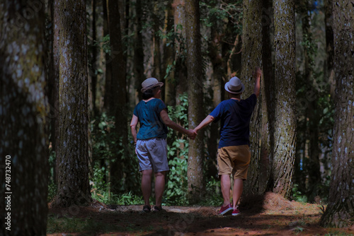 A woman and a man hold hands while exploring the forest photo