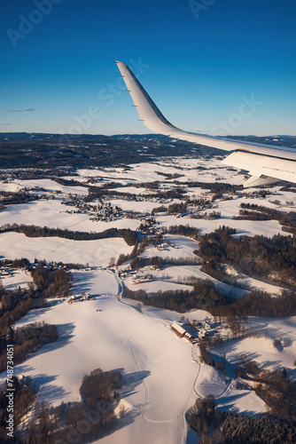 Airplane flying low over snowy mountains hills and preparing for landing to the airport, view from plane window of wing turbine and skyline