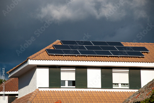 Solar panels on the roof of an orange tiled building on a cloudy, wintery day