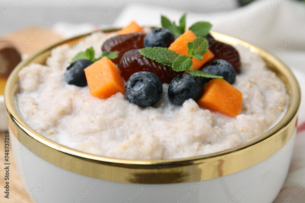 Delicious barley porridge with blueberries, pumpkin, dates and mint in bowl on table, closeup Delicious barley porridge with blueberries, pumpkin, dates and mint in bowl on table, closeup