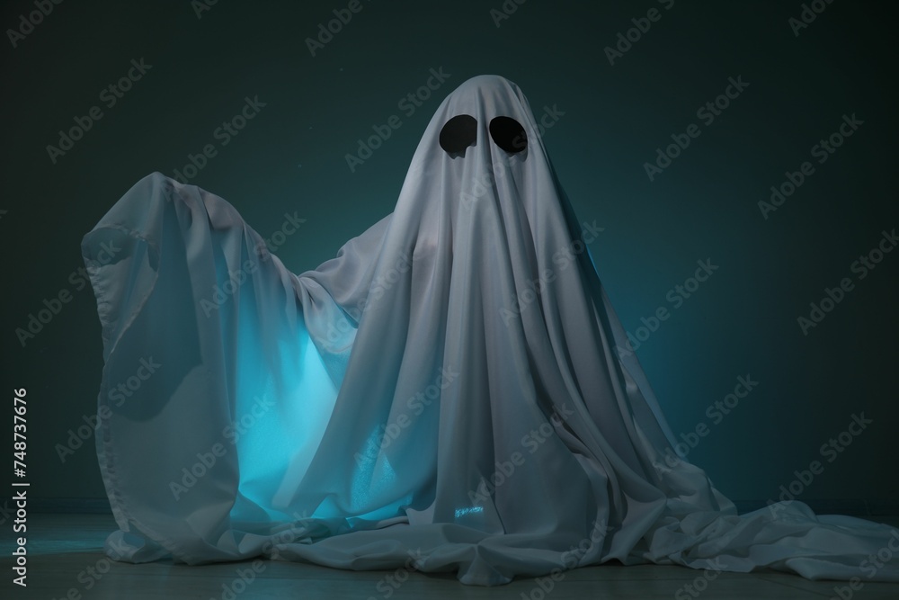 Creepy ghost. Woman covered with sheet on dark teal background