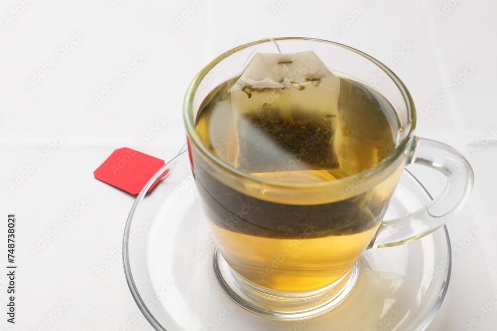 Tea bag in cup with hot drink on white table, closeup Tea bag in cup with hot drink on white table, closeup