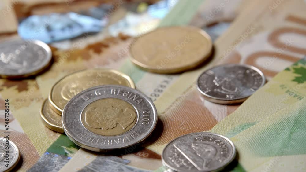 Canadian dollars and coins lie on banknotes of Canada different denominations and rotate in a circle. Canadian banknotes of different values. Banknotes Canadian currency. Canadian dollars and coins lie on banknotes of Canada different denominations and rotate in a circle. Canadian banknotes of different values. Banknotes Canadian currency.