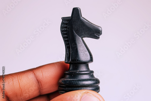 Hand holding black knight chess isolated on white, business strategy