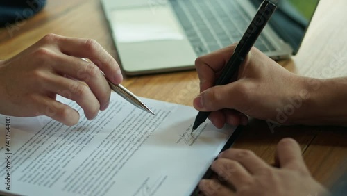 Male insurance agent in suit showing contract to client put a signature
