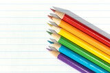 Pride flag created by a group of colored pencils on white lined paper. Copy space