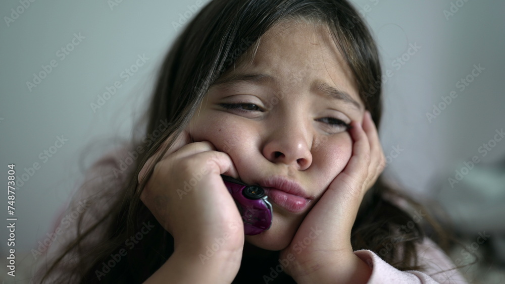 Close-up face of female Child feeling fatigue and boredom, exhausted kid holding head with hands gazing into the distance feeling lost in thought Close-up face of female Child feeling fatigue and boredom, exhausted kid holding head with hands gazing into the distance feeling lost in thought