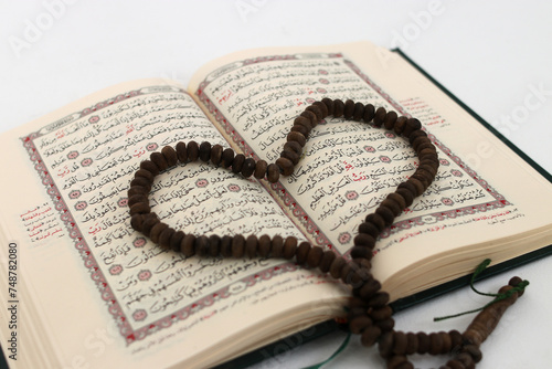 Prayer beads or Tasbih arranged in a heart shape on the Holy Quran, expressing love and devotion, isolated on a white background photo