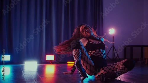 Sexy woman dancing twerk. Slow motion shooting. A dancer girl dances erotically in a dark hall. Twerk, high heels, striptease, a seductive dance. Atmospheric colored light, club, stage.	 photo