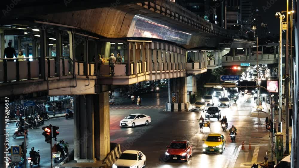 A bustling urban street scene at night with cars, motorcycles, and a ...