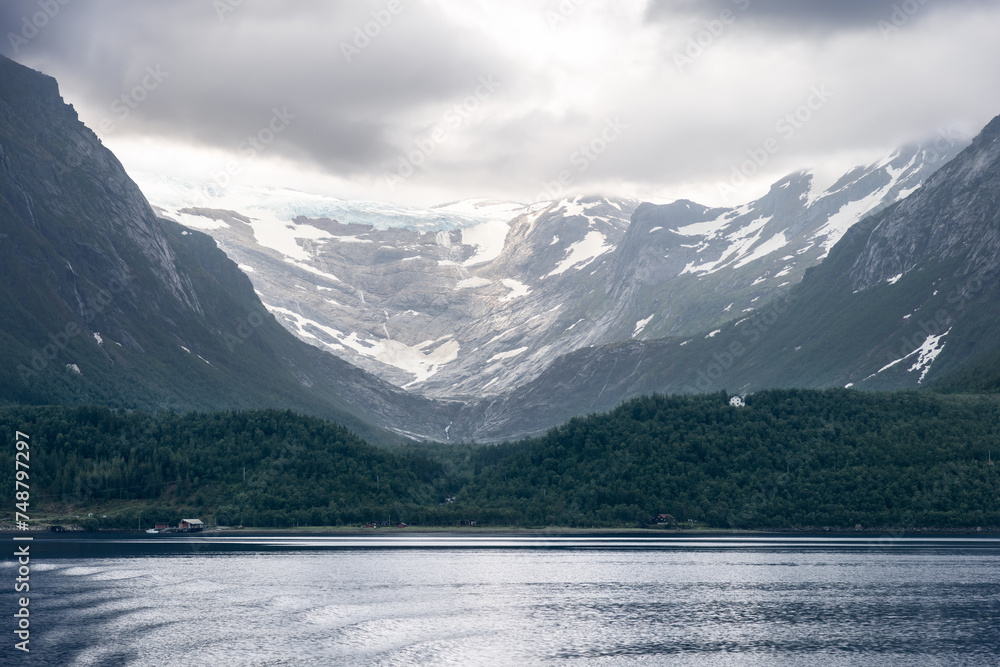 Svartisen Glacier, surrounded by lush green slopes and a mirror-like fjord, in a tranquil display of Norway's natural beauty