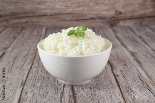 White rice in bowl on wood table. Close up