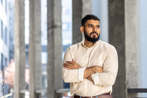 Confident man standing with arms crossed in a modern city environment