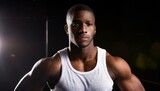 Close-up portrait of a very attractive, strong black man in white tank top on dark background