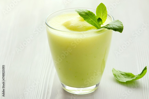 A refreshing glass of green smoothie garnished with a mint leaf on a white background, symbolizing health and vitality.