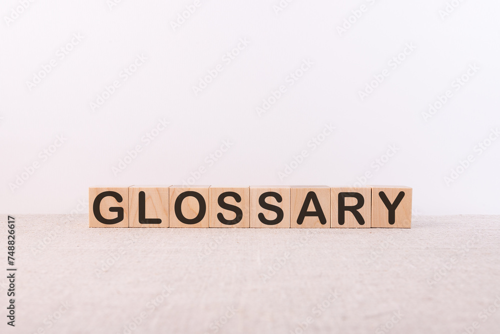 GLOSSARY word concept written on wooden cubes lying on a light table and light background. GLOSSARY word concept written on wooden cubes lying on a light table and light background.