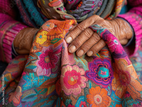 Detailed close-up photo of an elderly person's wrinkled hands resting on a vibrant, floral-patterned textile..