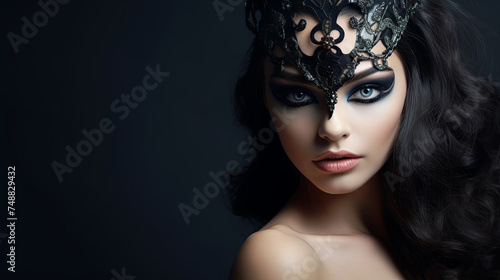 Portrait of seductive brunette in black carnival mask with gothic makeup on dark isolated background. Gothic style concept Female image of a crow bird for Halloween