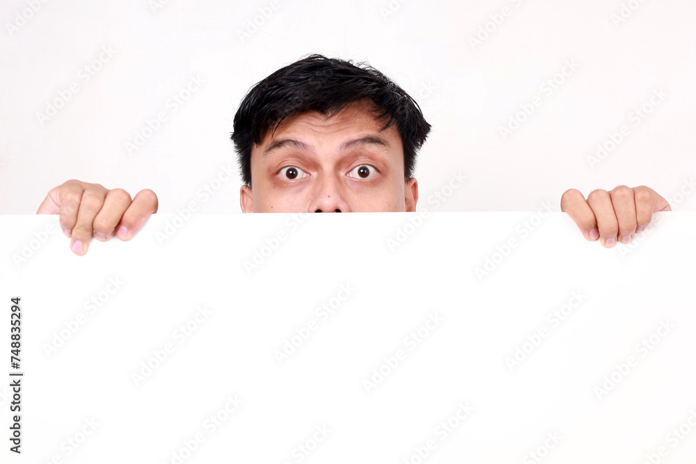 Portrait of young asian man standing behind an empty signboard Portrait of young asian man standing behind an empty signboard