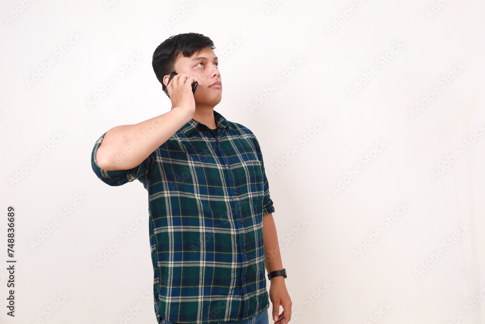 Side view of young asian man standing while on the phone Side view of young asian man standing while on the phone