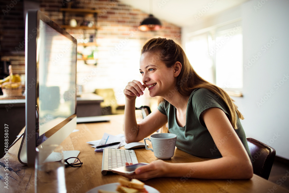 Focused young woman working on computer in home office setting Focused young woman working on computer in home office setting