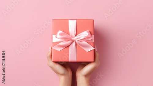 Hands holding festive gift box with satin ribbon for celebrations and special occasions