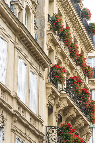 Beautiful parisian building decorated by red flowers; vertical picture