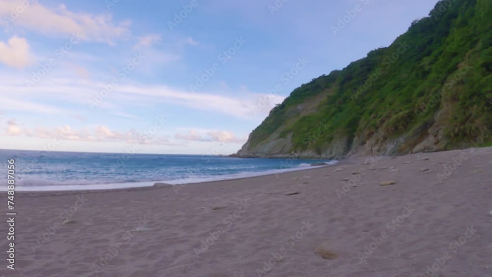 horizontal pane view of peaceful beach side with ocean sea salt water pounding lightly on to the shore look out to pacific horizon between mountain and man made embankment sunset pink clouds blue sky horizontal pane view of peaceful beach side with ocean sea salt water pounding lightly on to the shore look out to pacific horizon between mountain and man made embankment sunset pink clouds blue sky