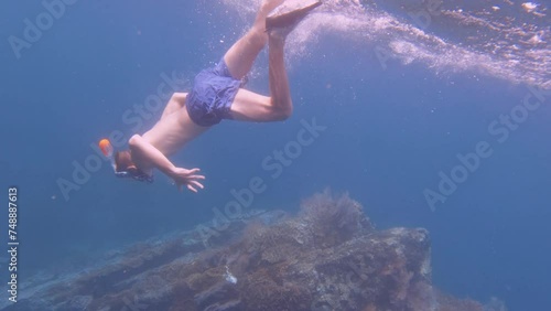 Wallpaper Mural a noob newbie white Caucasian teen male boy wearing snorkel mask and fin duck free diving kicking down into the deep blue ocean water to beautiful pink red gorgonian sea fan and finger leather corals Torontodigital.ca