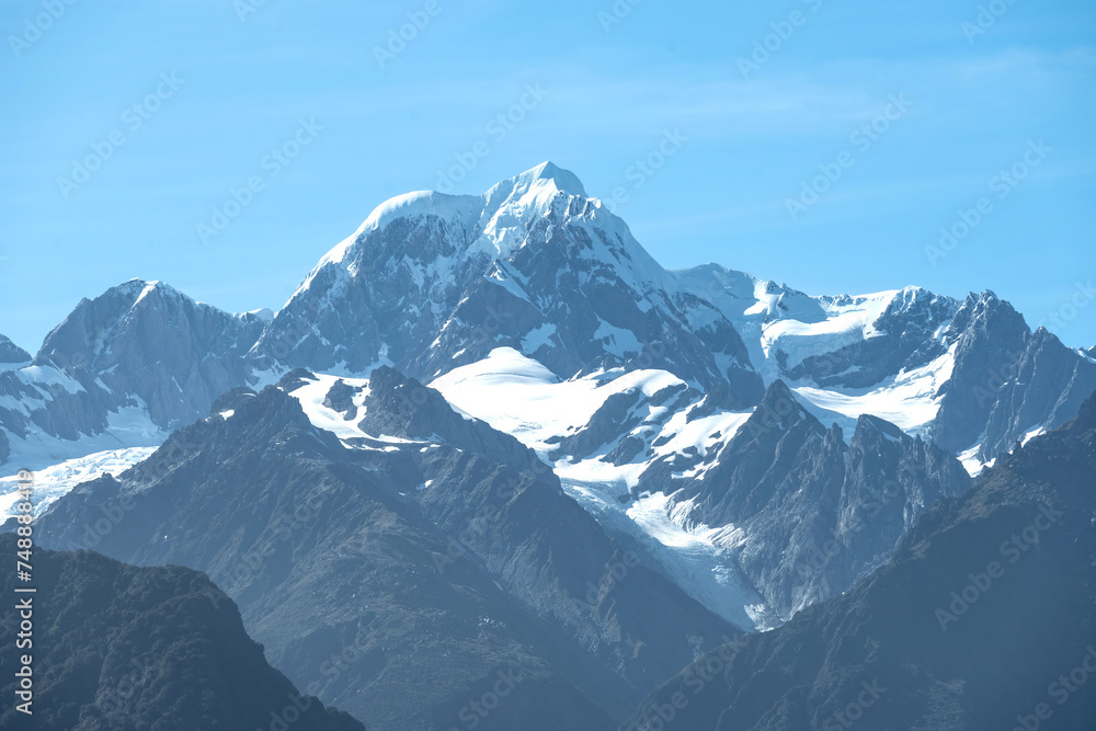 The view of Mt. Tasman peak, one of the famous landmark, near Mt. Cook in a fresh sunny day under blue sky, West Coast, New Zealand. The view of Mt. Tasman peak, one of the famous landmark, near Mt. Cook in a fresh sunny day under blue sky, West Coast, New Zealand.