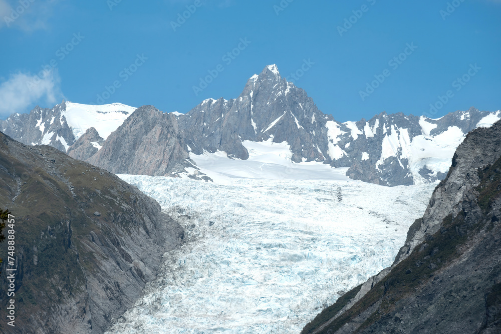 The close up scene of Fox Glacier peak landmark between mountains under fresh blue sky, Fox Glacier, West Coast, New Zealand.