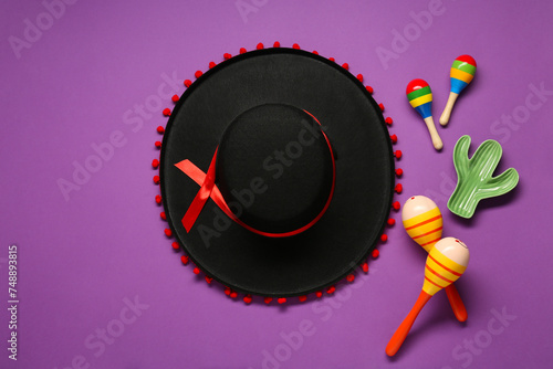 Mexican sombrero hat, maracas and toy cactus on purple background, flat lay