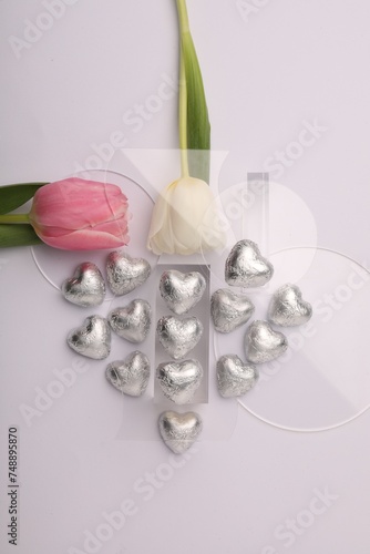 Fototapeta Naklejka Na Ścianę i Meble -  Heart made with delicious chocolate candies and beautiful tulips on white background, top view