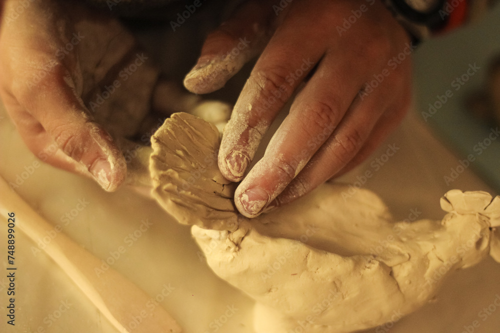 Fototapeta premium Child's hands sculpts a figurine from clay