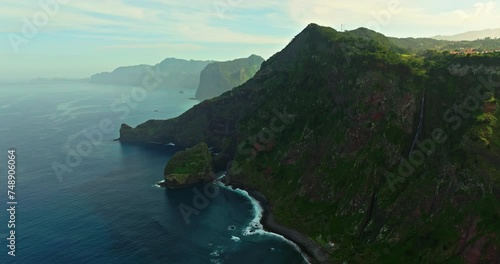 Coast of a green island in the Atlantic Ocean. Madeira landscape with mountains and ocean cliffs aerial drone shot. Breathtaking aerial view of the rugged coastline of Madeira Island photo