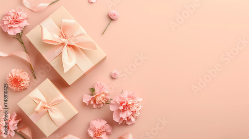 Mother's Day concept. Top view photo of two trendy gift boxes with ribbon bows and carnations on solid pastel peach color background with copy space