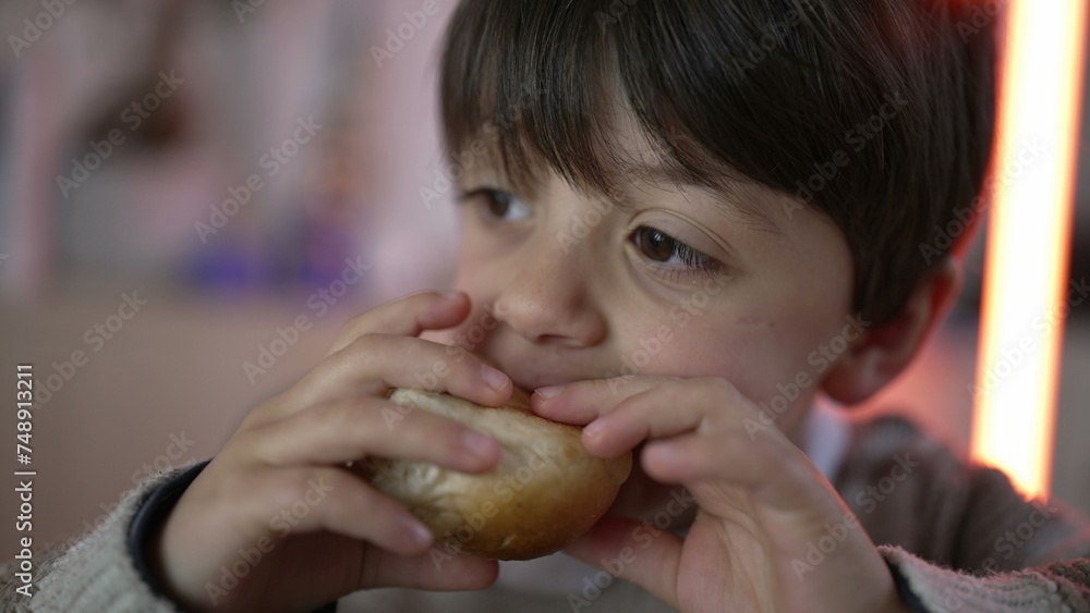 Close-up child's hand holding a piece of bread and taking a bite of rich carb food. Little boy snacking Close-up child's hand holding a piece of bread and taking a bite of rich carb food. Little boy snacking