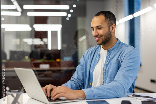 Canvas Print Smiling young Muslim man businessman, designer, freelancer, programmer in blue s