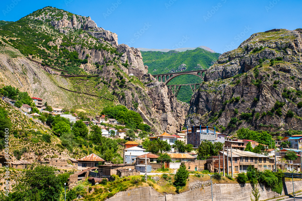 Iconic Trans-Iranian Railway Viaduct Amidst Rugged Cliffs and Residential Area in Iran