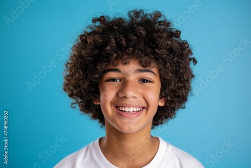 Smiling Teen Boy with Mixed Race and Curly Hair on Blue Background