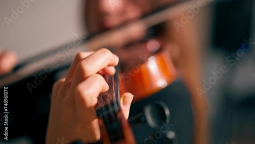 Close-up of a girl holding a violin with her fingers fingering the strings to perform classical musical composition photo