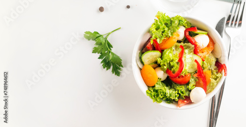 Bowl with salad with red and yellow tomatoes, peper, cucumbers, lettuce and mozzarella.