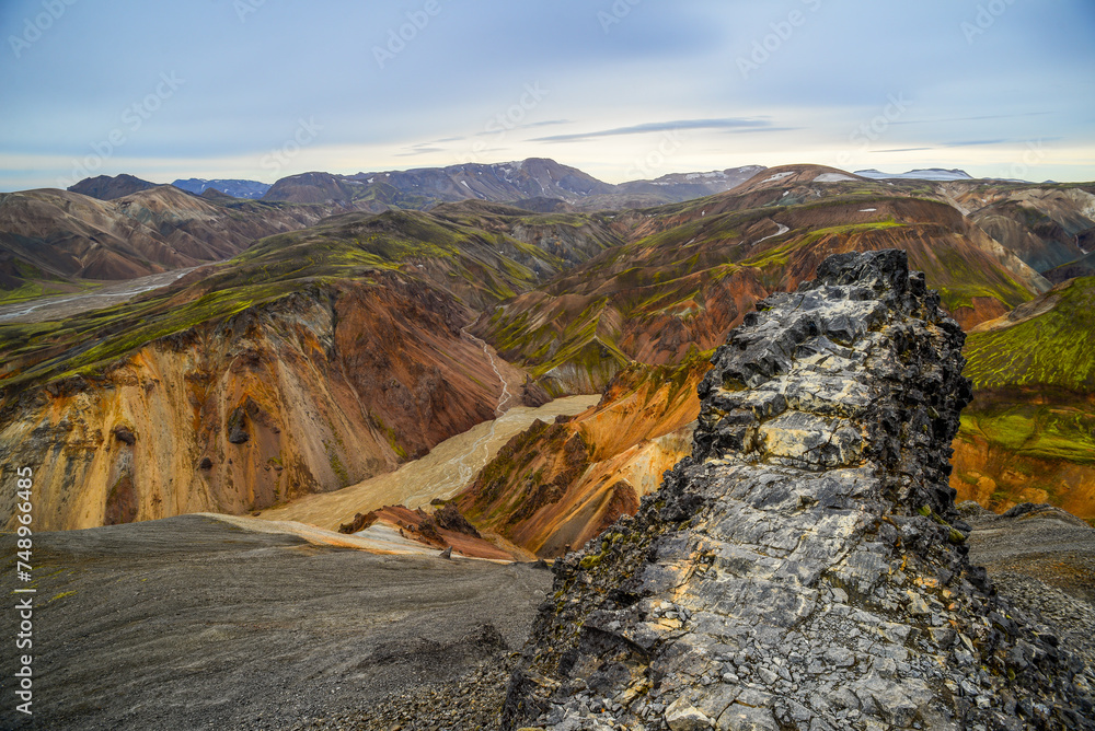 A rock outcrop on the summit of Bláhnjúkur volcano, surrounded by the glacial valleys and colorful volcanic mountains of Landmannalaugar, Fjallabak Nature Reserve, Central Highlands, Iceland.