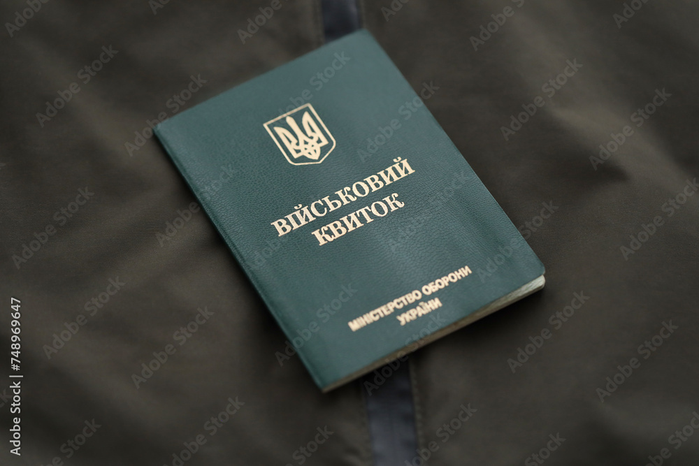 Military token or army ID ticket lies on green ukrainian military uniform indoors close up Military token or army ID ticket lies on green ukrainian military uniform indoors close up