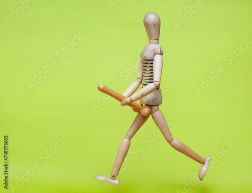 The wooden man is holding a stick in his hands that resembles a large erotic penis and is running after someone. Concept of large size, priapism and strong libido. Sexual maniac.