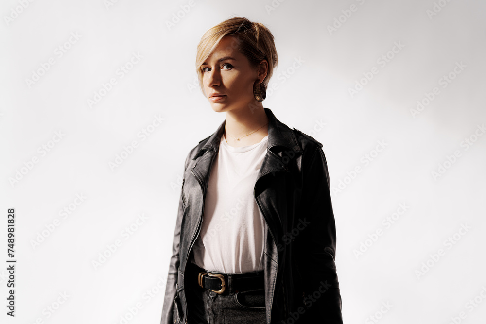 Side profile of a young woman in contemplative mood, highlighted by a dramatic shadow in leather jacket attire
